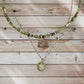 Collar de acero en color dorado con conchas y piedras verdes, con charm de huella