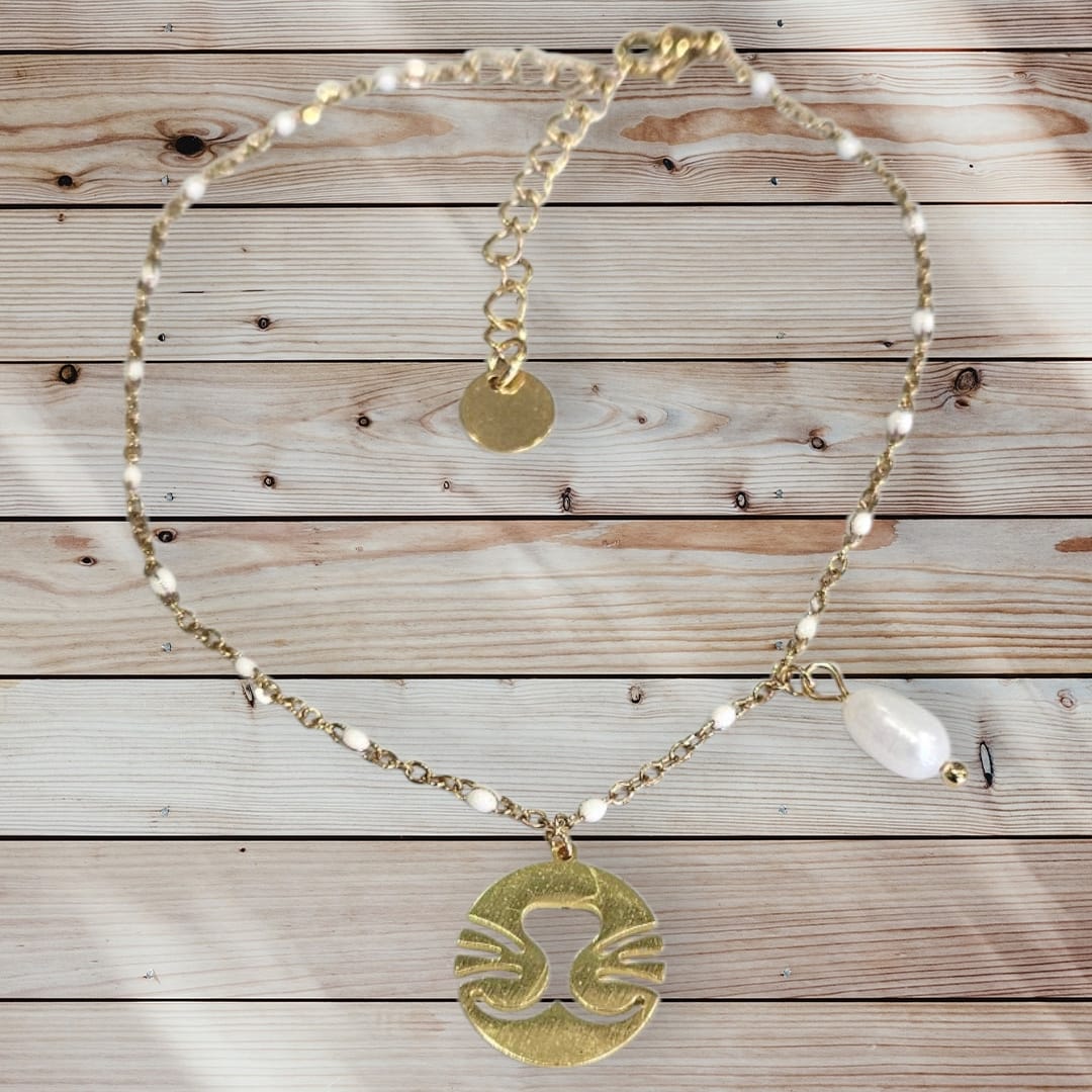 Tobillera de acero en color dorado con placa y perla.