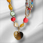 Collar de piedras y cristal de colores con corazón de acero lleno de huellas