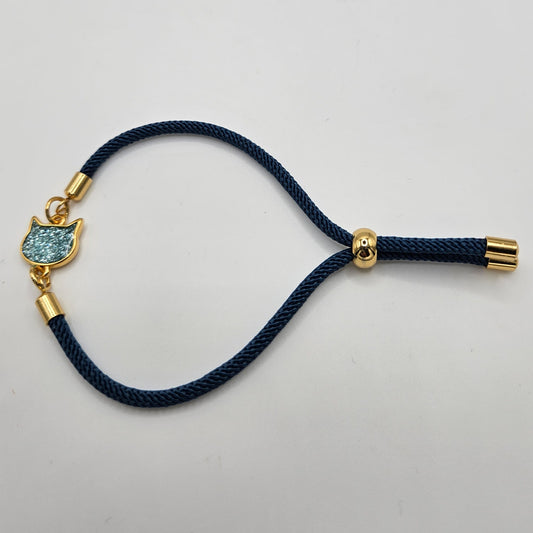 Pulsera de cordón trenzado en azul con fornituras de acero color dorado y cabeza de gatete esmaltado en azul brillante