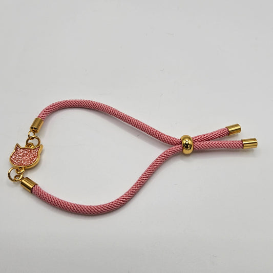 Pulsera de cordón trenzado en rosa con fornituras de acero color dorado y cabeza de gatete esmaltado en rosa brillante